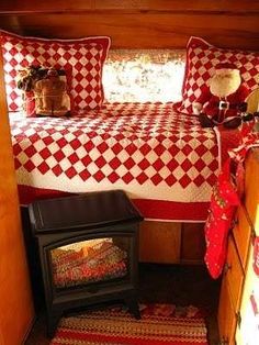 a bed with red and white checkered bedspread next to a small stove