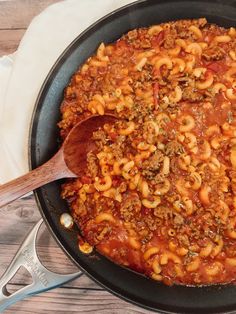 a skillet filled with macaroni and cheese on top of a wooden table