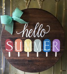 a wooden sign with the words hello summer painted on it and a green bow hangs from a door