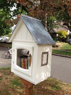 a white bird house with books in the window