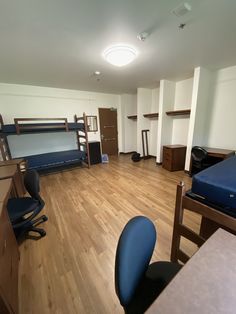 an empty room with bunk beds, desks and other items on the wooden floor