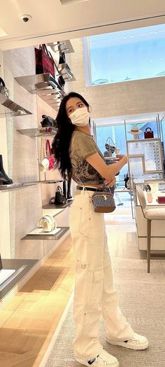 a woman wearing a face mask standing in front of a shoe store display with shoes on shelves