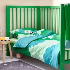 a child's bed with green and blue sheets