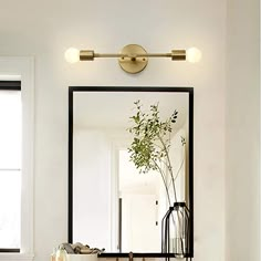 a bathroom with a sink, mirror and lights on the wall above it's counter