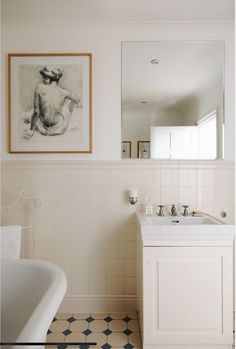 a bathroom with a sink, mirror and bathtub next to a painting on the wall