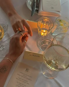 two people holding hands at a table with wine glasses and menus on it,