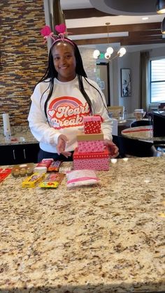 a woman standing behind a counter holding a box with some candy on top of it