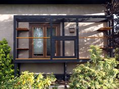 a black and brown building with shelves on the outside, surrounded by bushes and trees