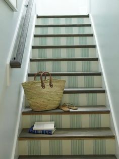 a basket sitting on top of some steps next to a handbag and bookcase