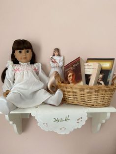 a doll sitting on top of a shelf next to a basket with books in it