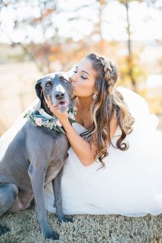 a woman in a wedding dress kissing her dog