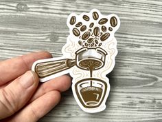 a hand holding a sticker with coffee pouring out of it