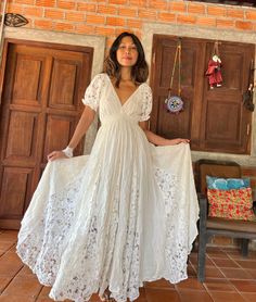 a woman in a white dress standing next to wooden doors