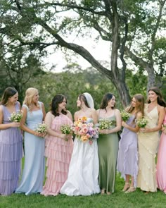 a group of women standing next to each other on top of a lush green field