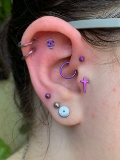 a woman with purple ear piercings and a cross on her left side behind the ear