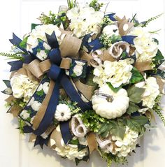 a wreath with white flowers and blue ribbon