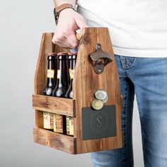 a person holding a wooden beer caddy with bottles in it and a bottle opener