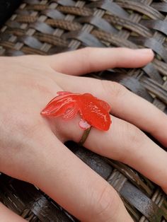 a person's hand with a ring on it and a red flower in the middle