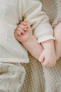 a baby laying on top of a white blanket