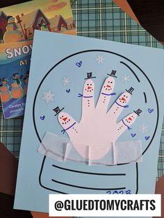 a snow globe with two paper snowmen in it and the words gluetomycrafts on top