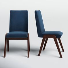 two blue chairs sitting side by side next to each other on a white surface with one chair facing the other