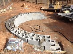 an outdoor area with concrete blocks being laid on the ground and some tools laying around it