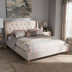 a bedroom with a bed, nightstands and painting on the wall behind it in neutral colors