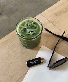 a green drink sitting on top of a wooden table next to a pair of scissors