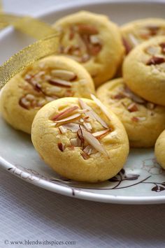 a plate filled with cookies covered in nuts and topped with a gold ribbon on top