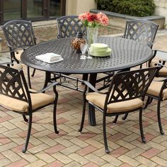 an outdoor dining table and chairs on a brick patio with potted flowers in the center