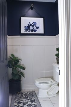 a white toilet sitting in a bathroom next to a plant