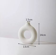 a white vase sitting on top of a table next to a measuring line with measurements