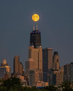 the full moon is setting over skyscrapers in new york city