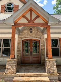 the front entrance to a home with stone pillars and wood beams on it's sides