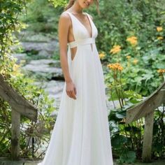 a woman wearing a white dress standing in the woods