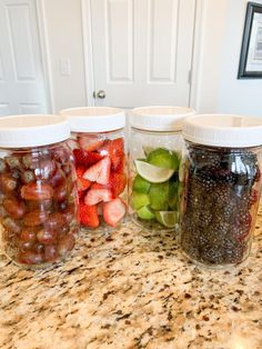 four jars filled with fruit sitting on top of a counter