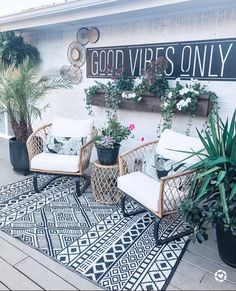 two wicker chairs sitting on top of a black and white rug next to potted plants