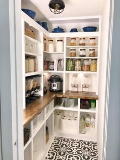 a kitchen with white cabinets and black and white floor tiles on the floor is an open pantry