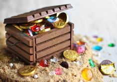 there is a small chocolate box in the sand with coins coming out of it and on top