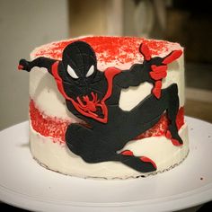 a spiderman cake with white frosting and red sprinkles on it