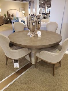 a round table with chairs around it at a furniture store in the middle of a room