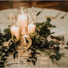 there are candles on the table with greenery