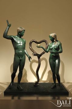 two statues are standing next to each other with their arms in the shape of a heart