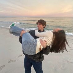 a man carrying a woman on his back at the beach