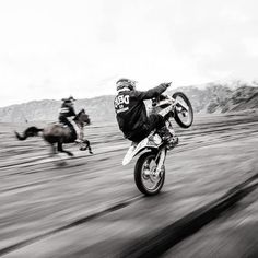 black and white photograph of two people riding motorcycles