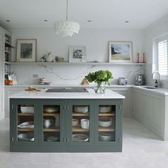 a kitchen filled with lots of white counter tops and drawers next to a sink under a light fixture