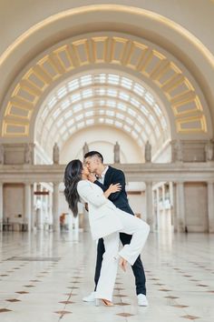 a man and woman are dancing in an ornate building with large arches on the ceiling