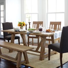 a dining room table with two benches in front of it and sunflowers on the window sill