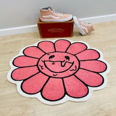 a pink rug with a smiling flower on the floor in front of a pair of sneakers