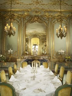 a fancy dining room set up for a formal dinner with white tablecloths and yellow chairs